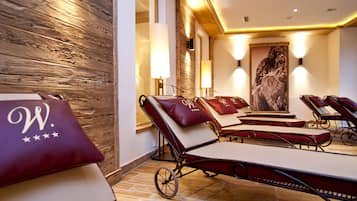 A spa area with reclining chairs, wooden walls, and wall-mounted lamps.