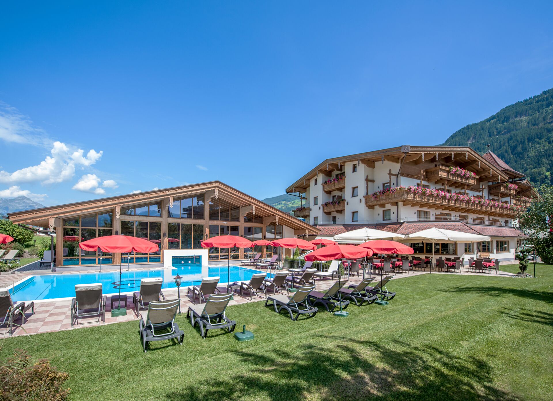 Un hotel con piscina, mobiliario exterior y vistas a la montaña.