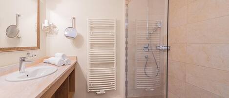 A modern bathroom with a sink, mirror, towel rack, and glass-enclosed shower.