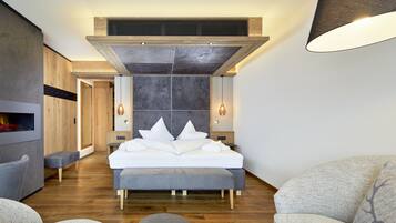 Un dormitorio moderno con una cama grande, un banco empotrado, una chimenea y un aplique de pared.