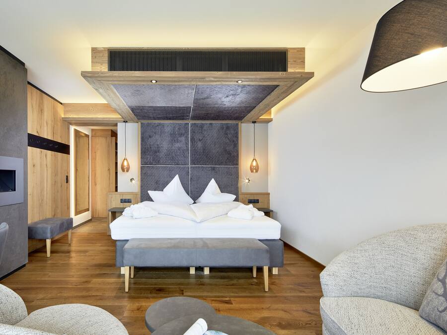 Un dormitorio moderno con una cama grande, un banco empotrado, una chimenea y un aplique de pared.