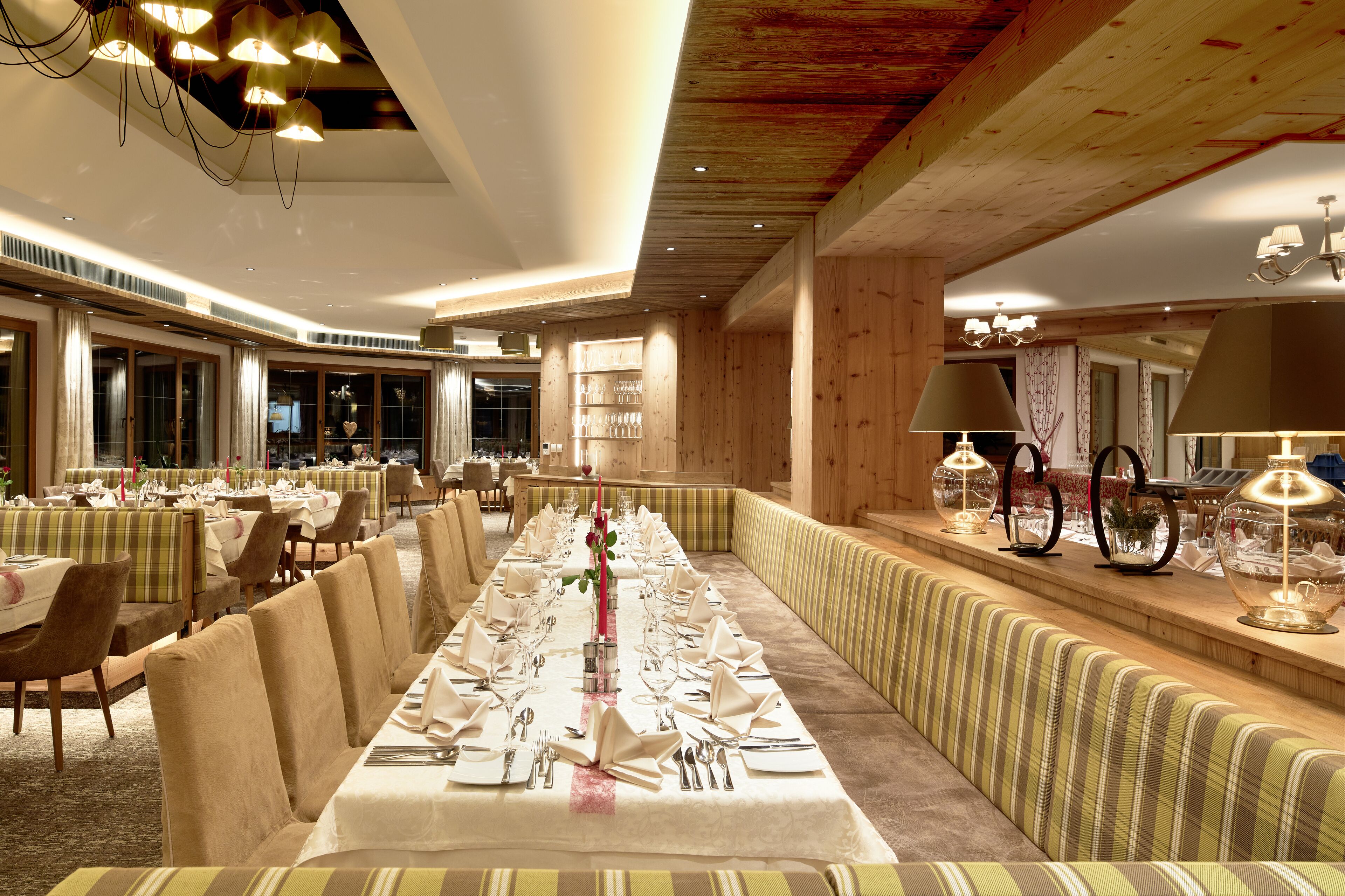 A long dining table set for a formal meal, surrounded by upholstered seating.