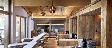 A wooden interior with a long bench seating area, a sofa, and a bed.