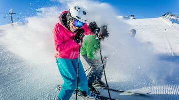 A person skiing on a snowy slope with a clear blue sky.