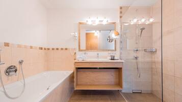 A modern bathroom with a bathtub, a vanity with a mirror, and a shower area.