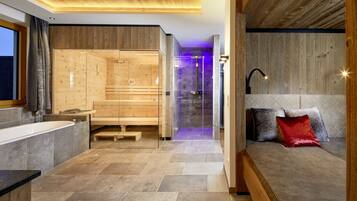 A modern bathroom with a wooden vanity, a glass-enclosed shower, and a seating area with cushions.