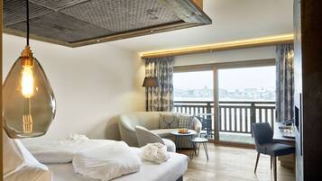 A modern hotel room with a bed, a sofa, a desk, and a balcony with a view.