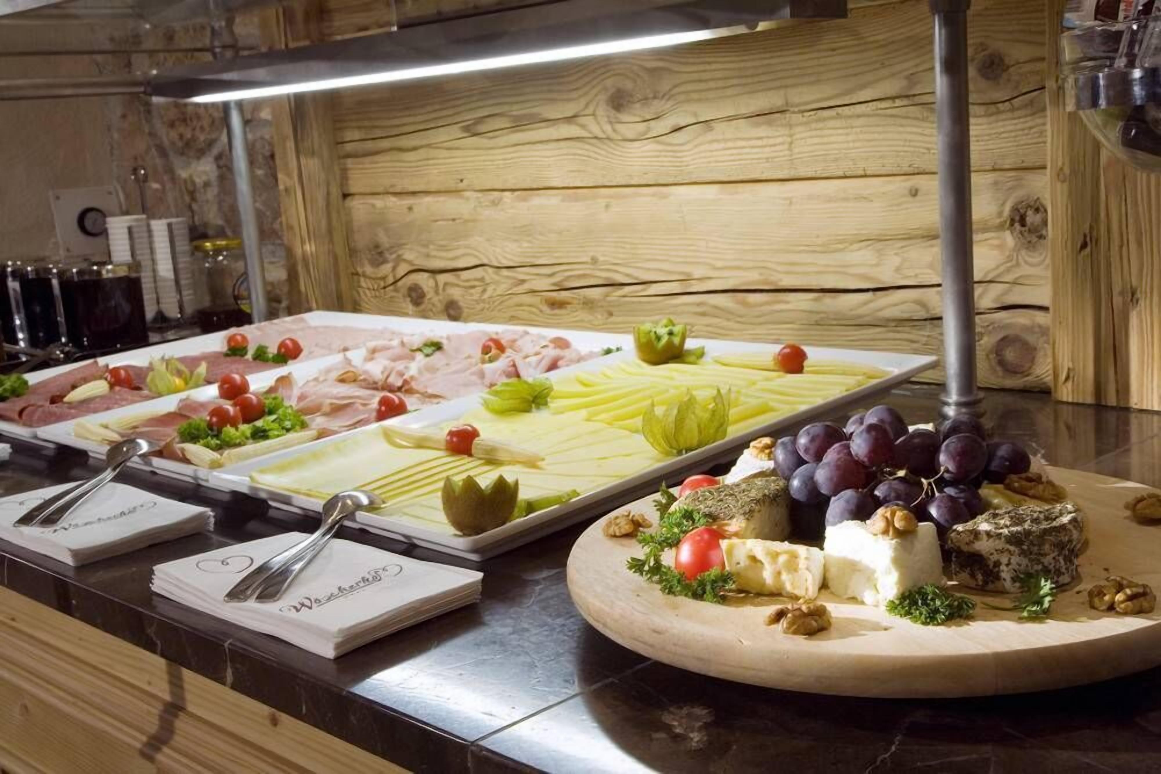Un bufé con diversas opciones de comida, incluyendo carnes, quesos y frutas.