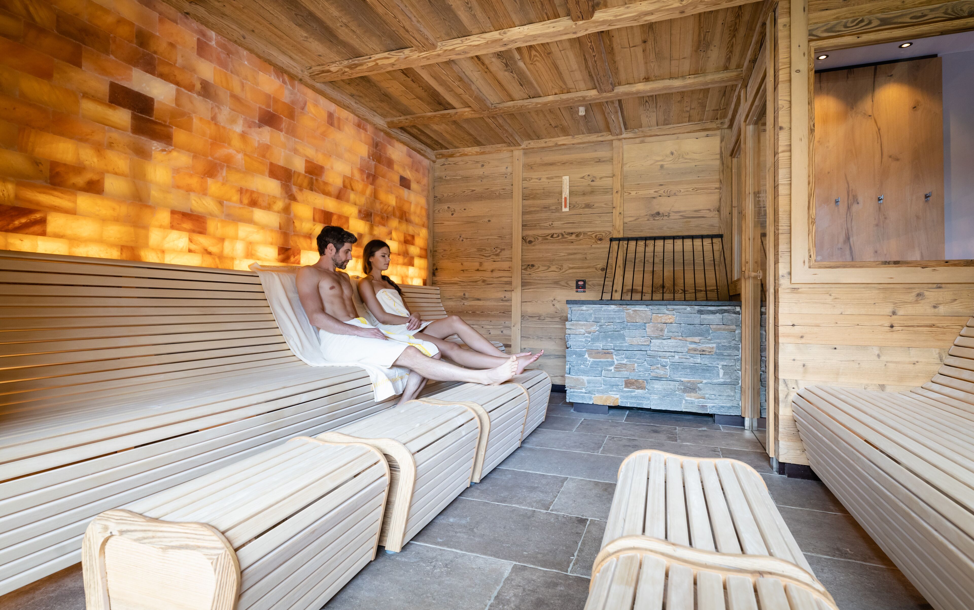 A sauna with wooden benches and a stone wall.