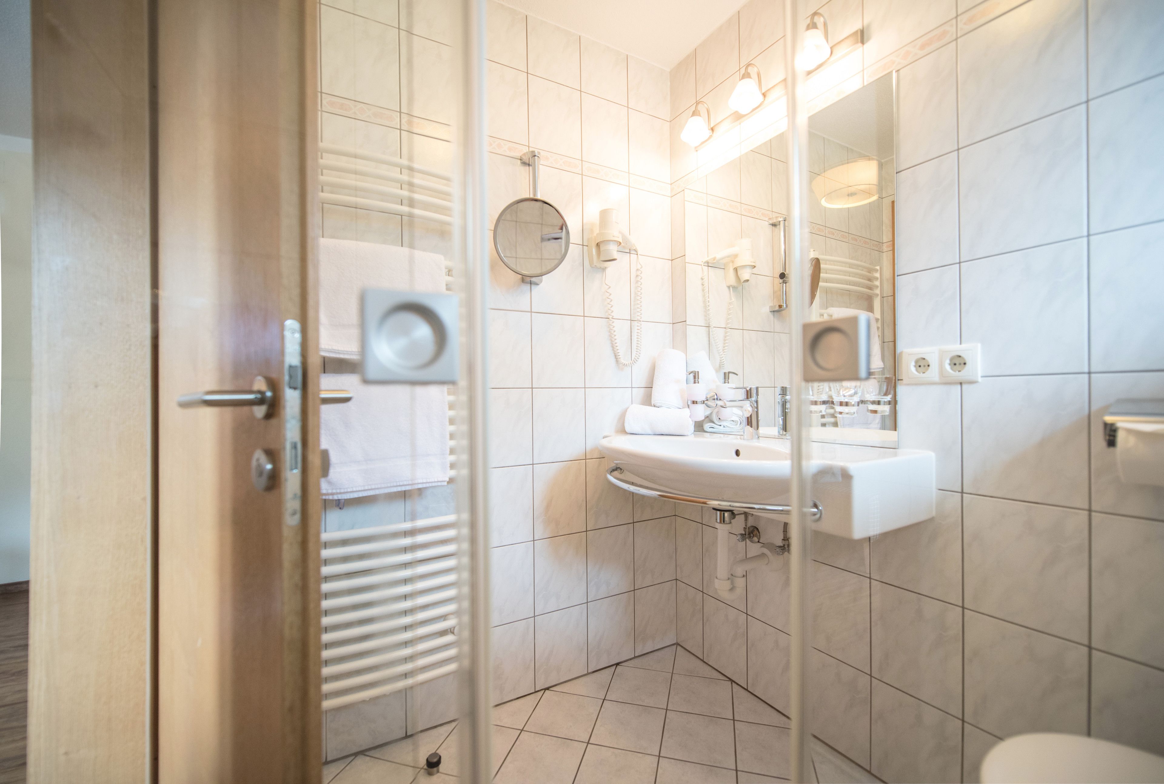 A modern bathroom with a glass shower door, a sink with a mirror, and a toilet.