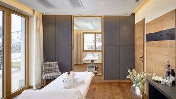 A hotel room with a bed, a chair, a mirror, a wooden cabinet, and a window.