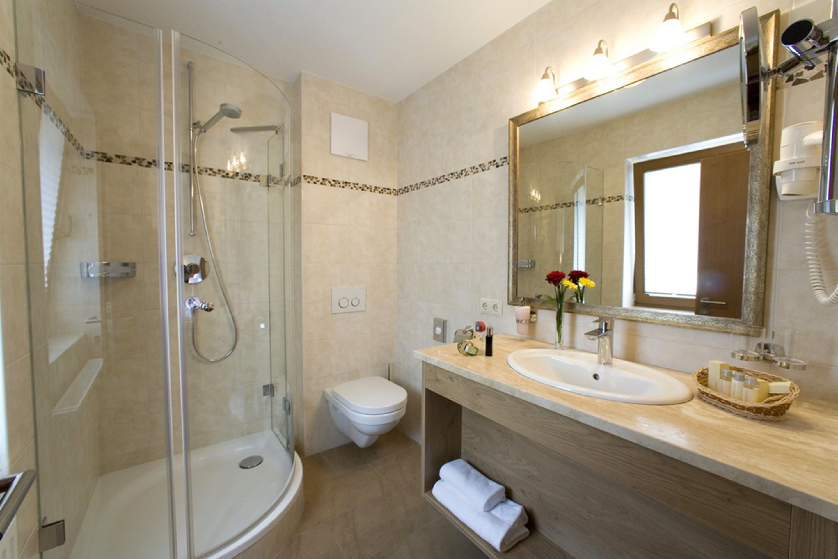 Een moderne badkamer met een douchecabine van glas, een wit toilet en een wastafelmeubel met een wastafel en spiegel.