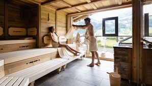 A wooden sauna with benches and a stone wall. - Wöscherhof (Uderns)