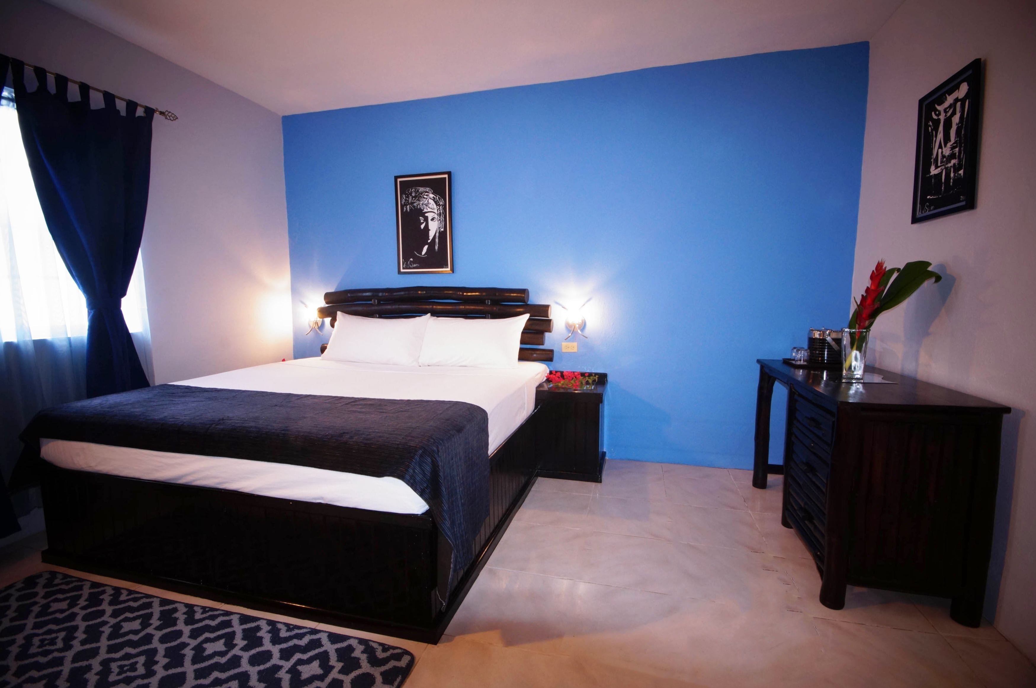 A bedroom with a large bed, a nightstand, a dresser, and a framed picture on the wall.