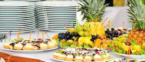 Een buffet met diverse gerechten en een stapel borden op de achtergrond.