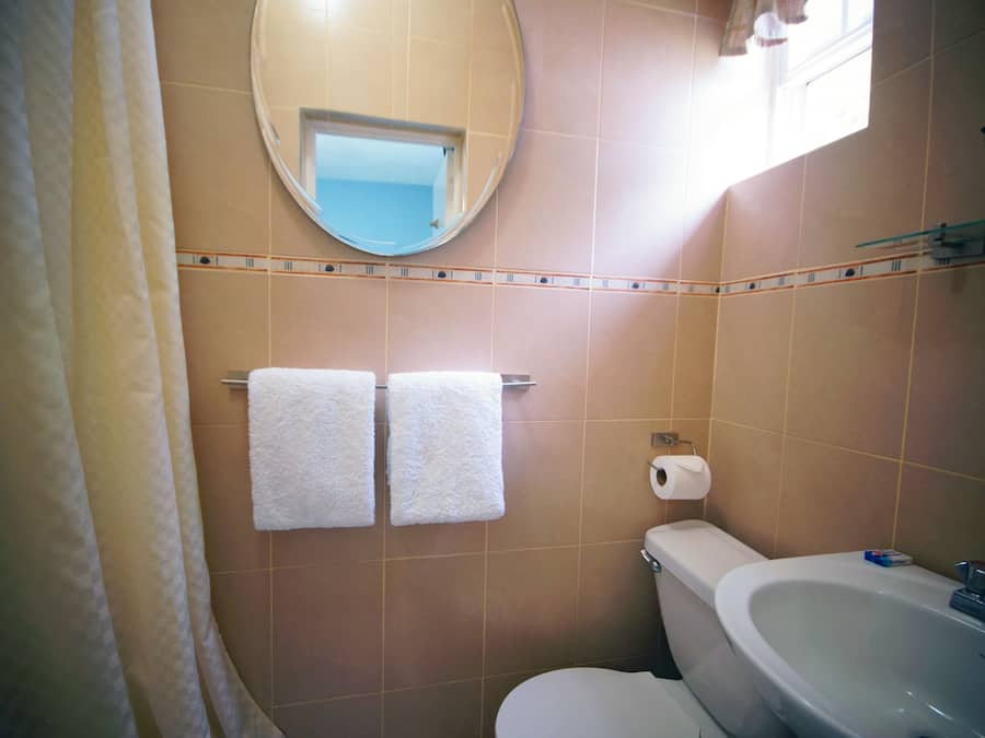 A bathroom with two white towels hanging on a rack, a toilet, a sink, and a mirror on the wall.