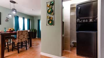 A kitchen with a stainless steel refrigerator, a dining area with a table and chairs, and a wall-mounted decorative piece.