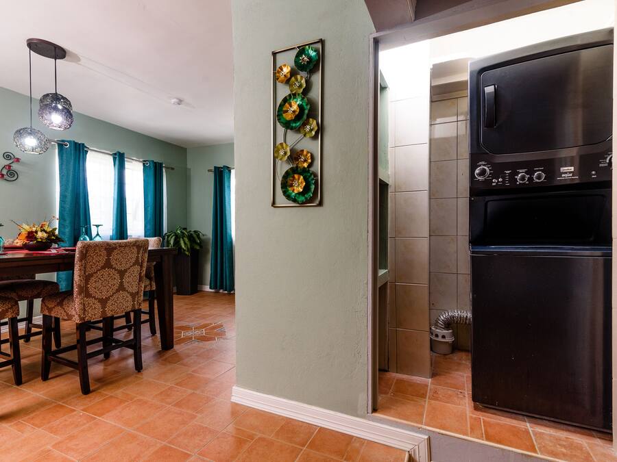 A kitchen with a stainless steel refrigerator, a dining area with a table and chairs, and a wall-mounted decorative piece.