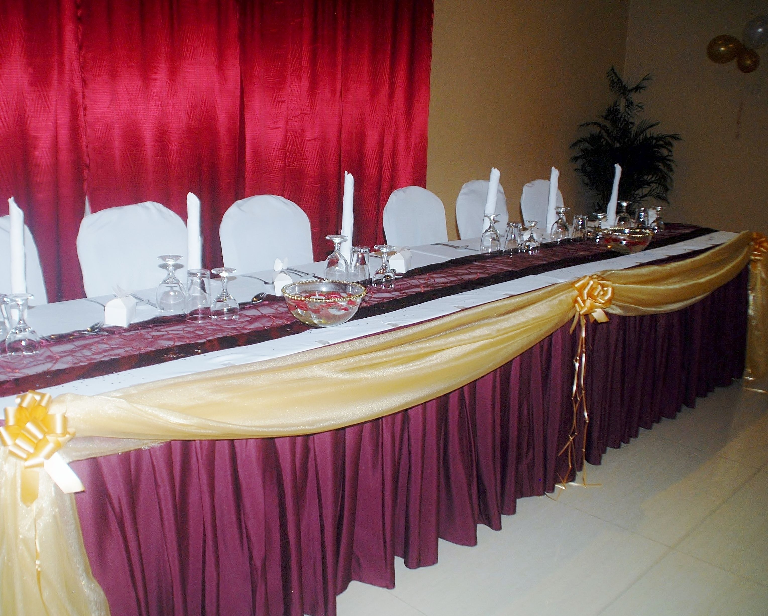A banquet table with a draped tablecloth, white chairs, and candles.