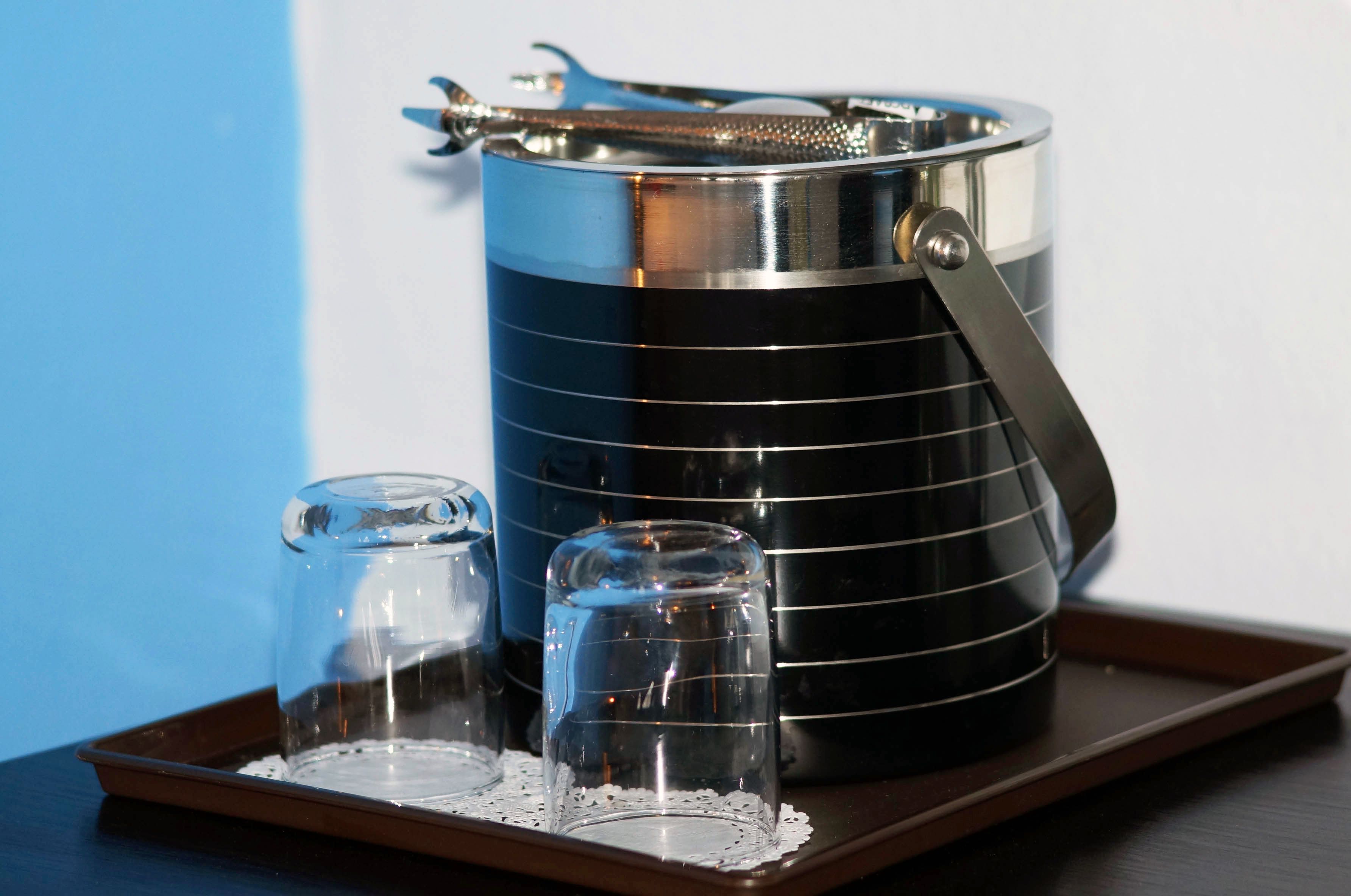 A stainless steel kettle with a handle and spout, a glass carafe, and a glass teapot on a tray.
