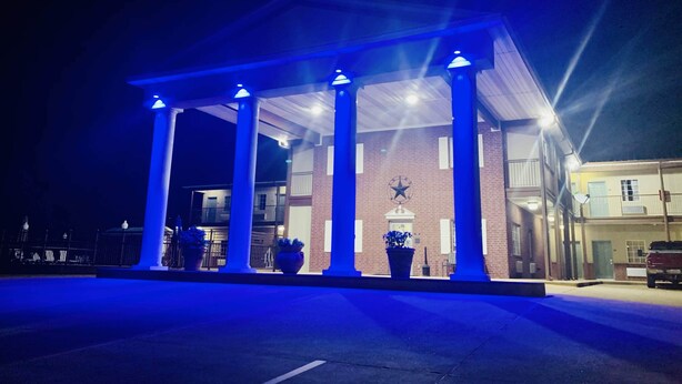 A gas station with a blue-lit canopy and a brick building in the background. - Weston Inn & Suites (Rusk)