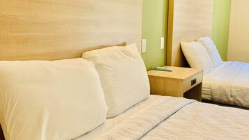 Una habitación de hotel con una cama, una mesita de noche y un espejo.