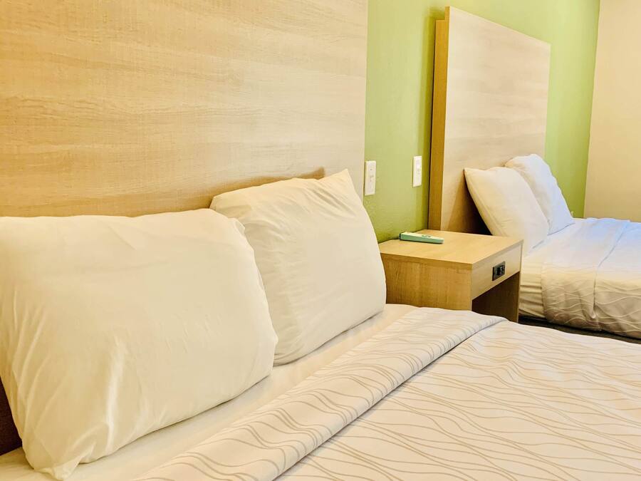 Una habitación de hotel con una cama, una mesita de noche y un espejo.