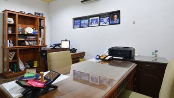 A well-organized office with a wooden desk, computer, printer, and a bookshelf filled with books and binders.