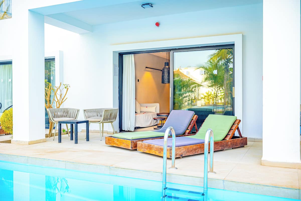 Un área junto a la piscina con sillones de descanso, una mesita y un sofá.