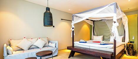 A bedroom with a bed, a sofa, a small table, and a hanging light fixture.