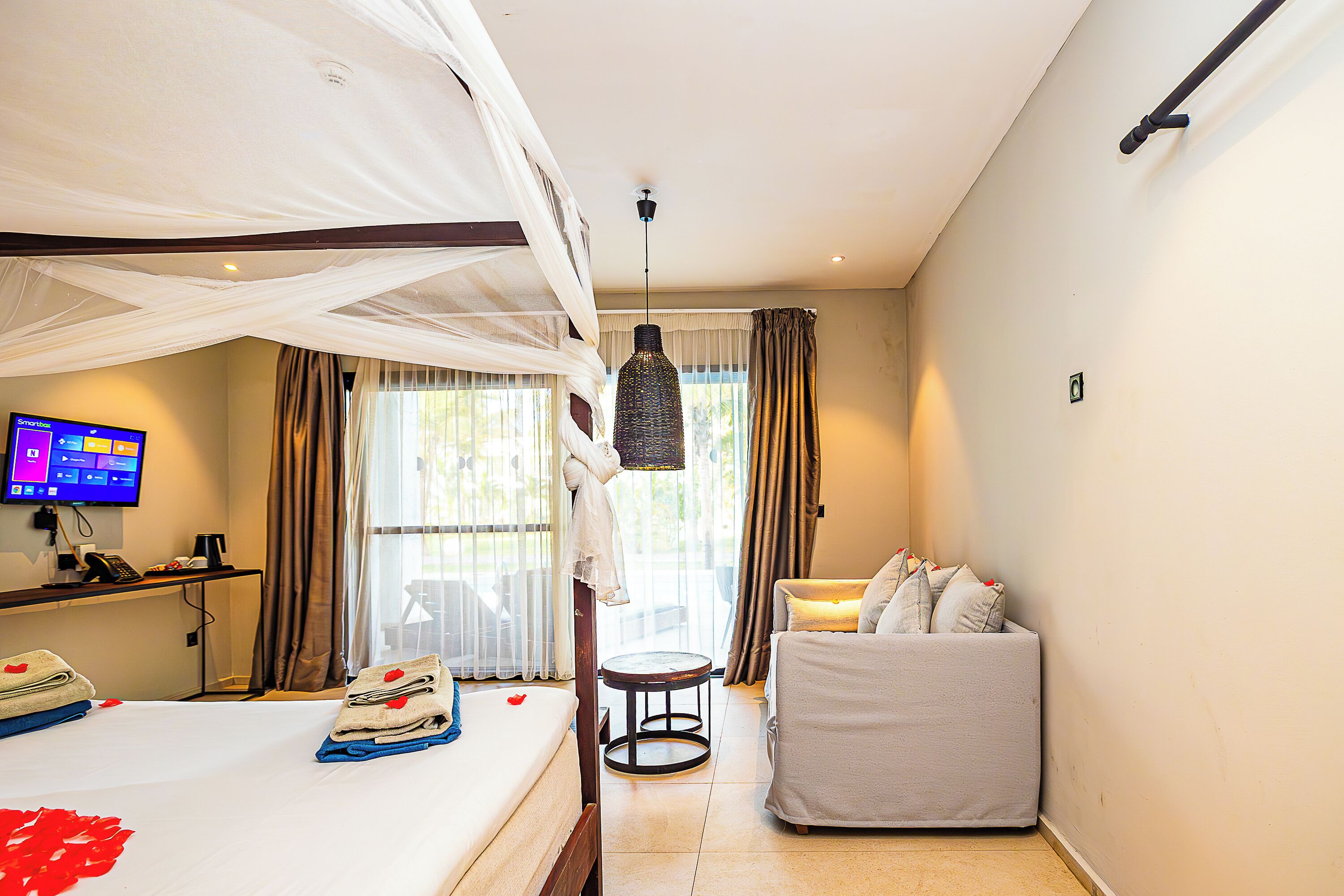 A hotel room with a bed, a desk with a computer, a chair, and a small table.