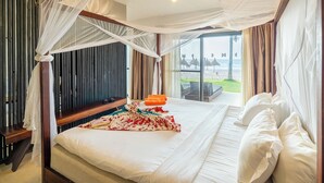 A bed with a canopy, a bedside table, and a view of the beach.
