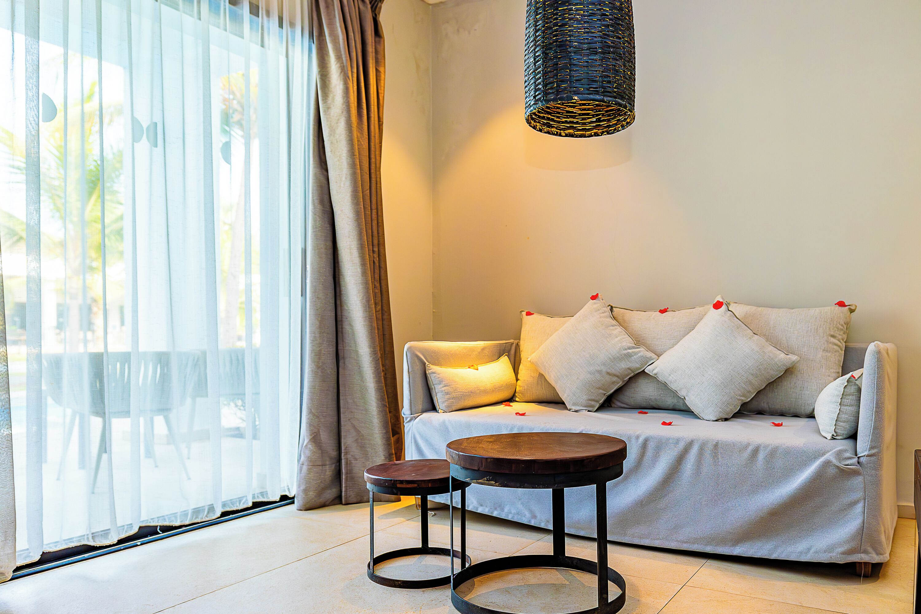 A modern living room with a sofa, two small tables, and a hanging light fixture.