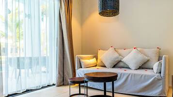 A modern living room with a sofa, two small tables, and a hanging light fixture.