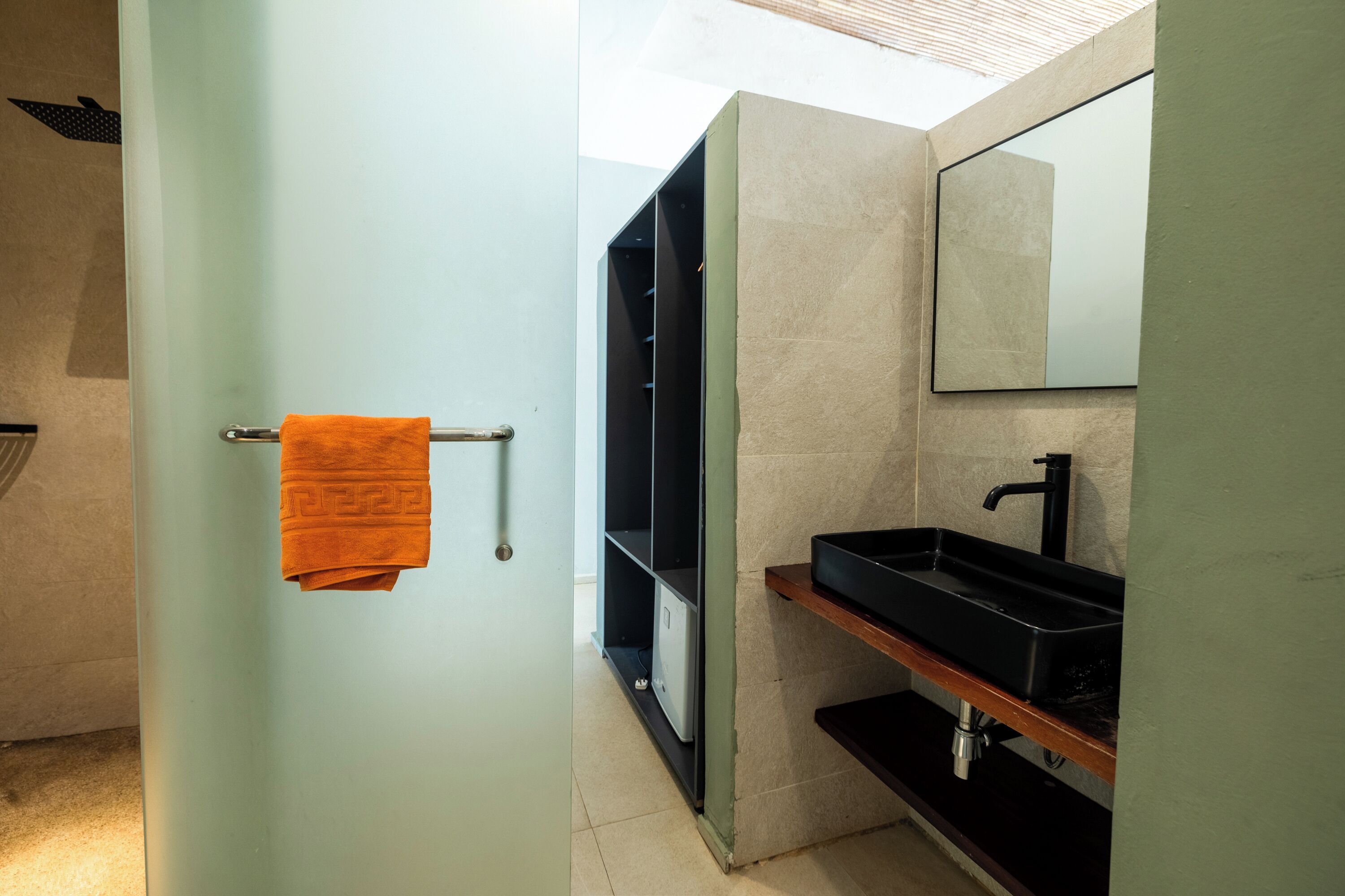 A bathroom with a towel rack, a black sink, and a mirror.