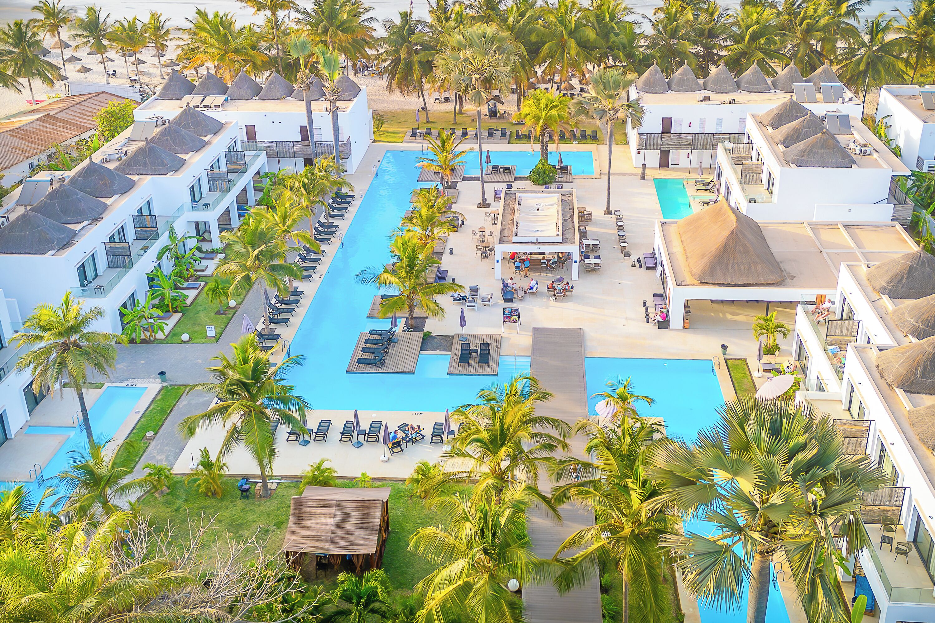 Un resort con varias piscinas, palmeras y zonas de playa.