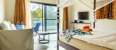 A room with a bed, a chair, a TV, and a balcony with curtains.