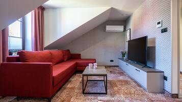 A modern living room with a red sofa, a coffee table, and a TV on a white cabinet.
