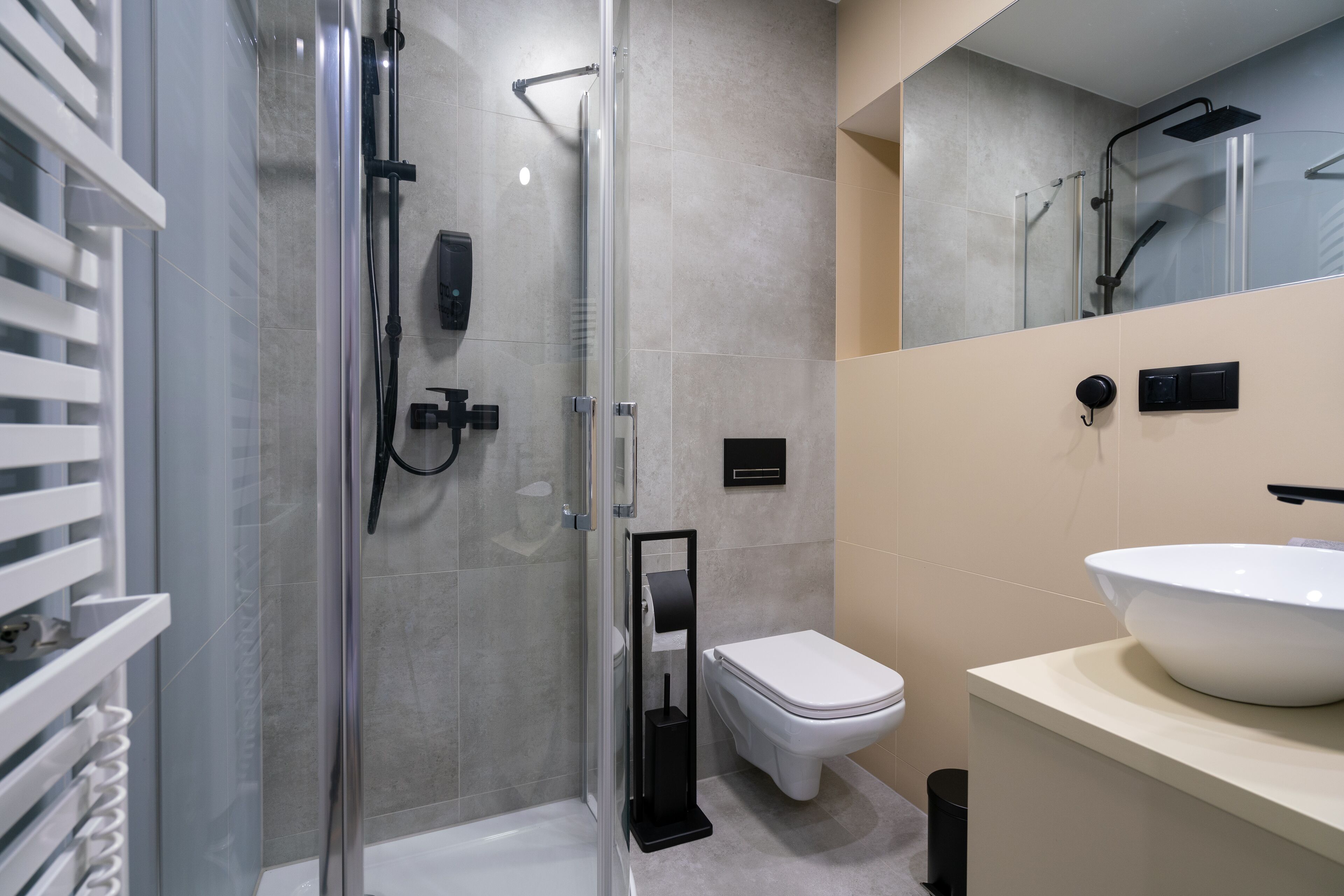 A modern bathroom with a glass-enclosed shower, a white toilet, and a large white sink.