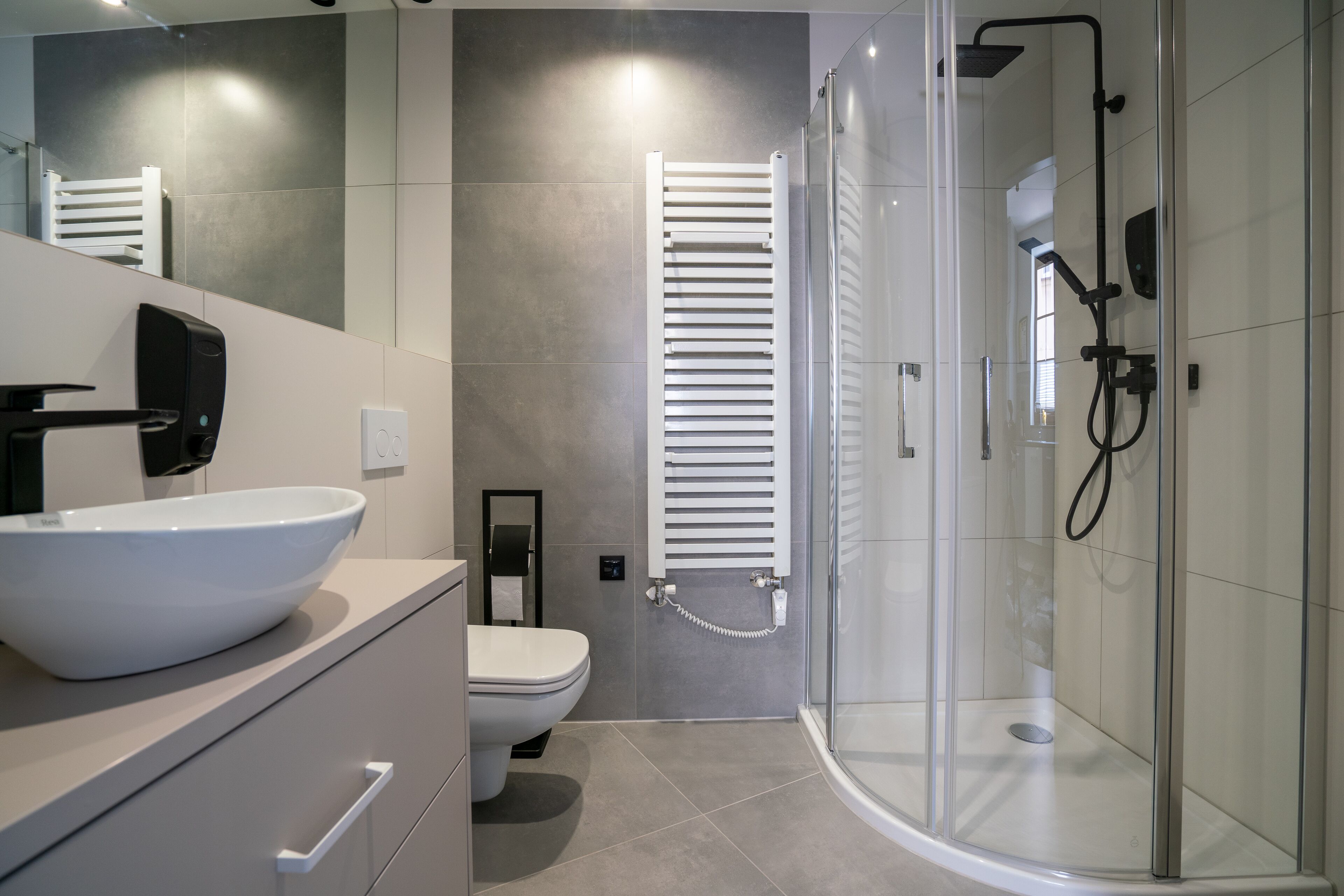 Un baño moderno con lavamanos blanco, inodoro y zona de ducha con mampara de vidrio.