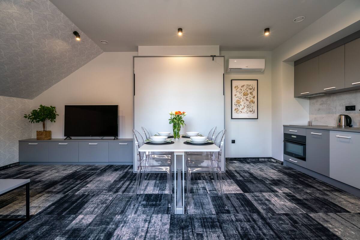 A modern kitchen with grey cabinets, a built-in oven, and a coffee machine.