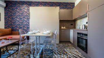 Una cocina moderna con comedor, que incluye una alfombra estampada, sillas traslúcidas y un sofá.