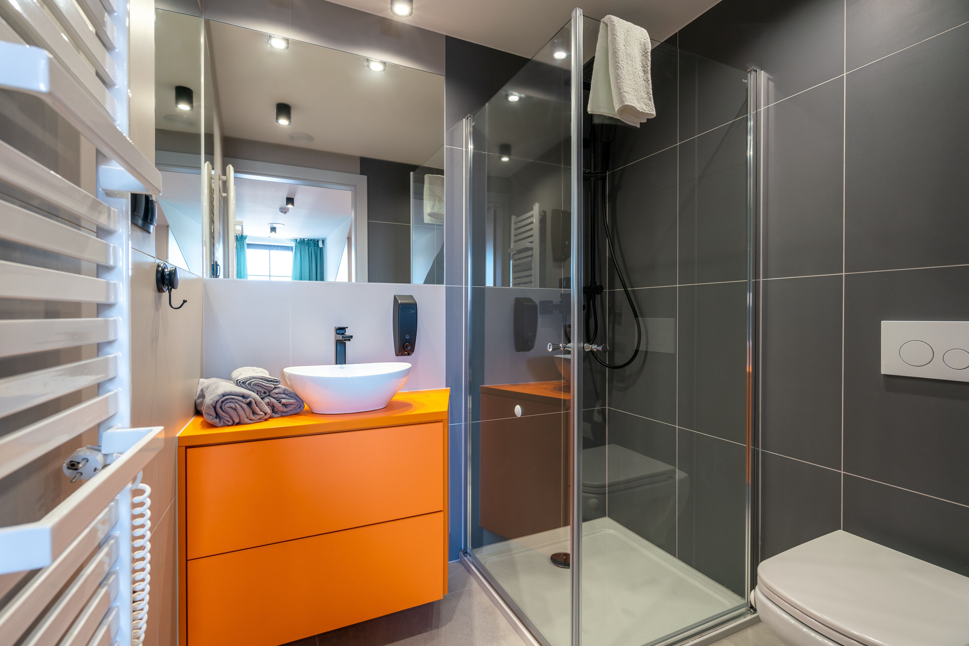 A modern bathroom with a glass shower enclosure, a white sink, and a wooden vanity.