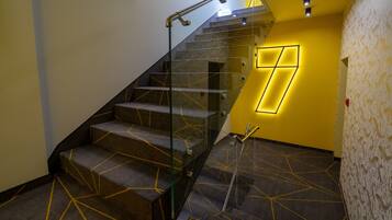 Una escalera moderna con barandillas de vidrio y alfombra con motivos geométricos.