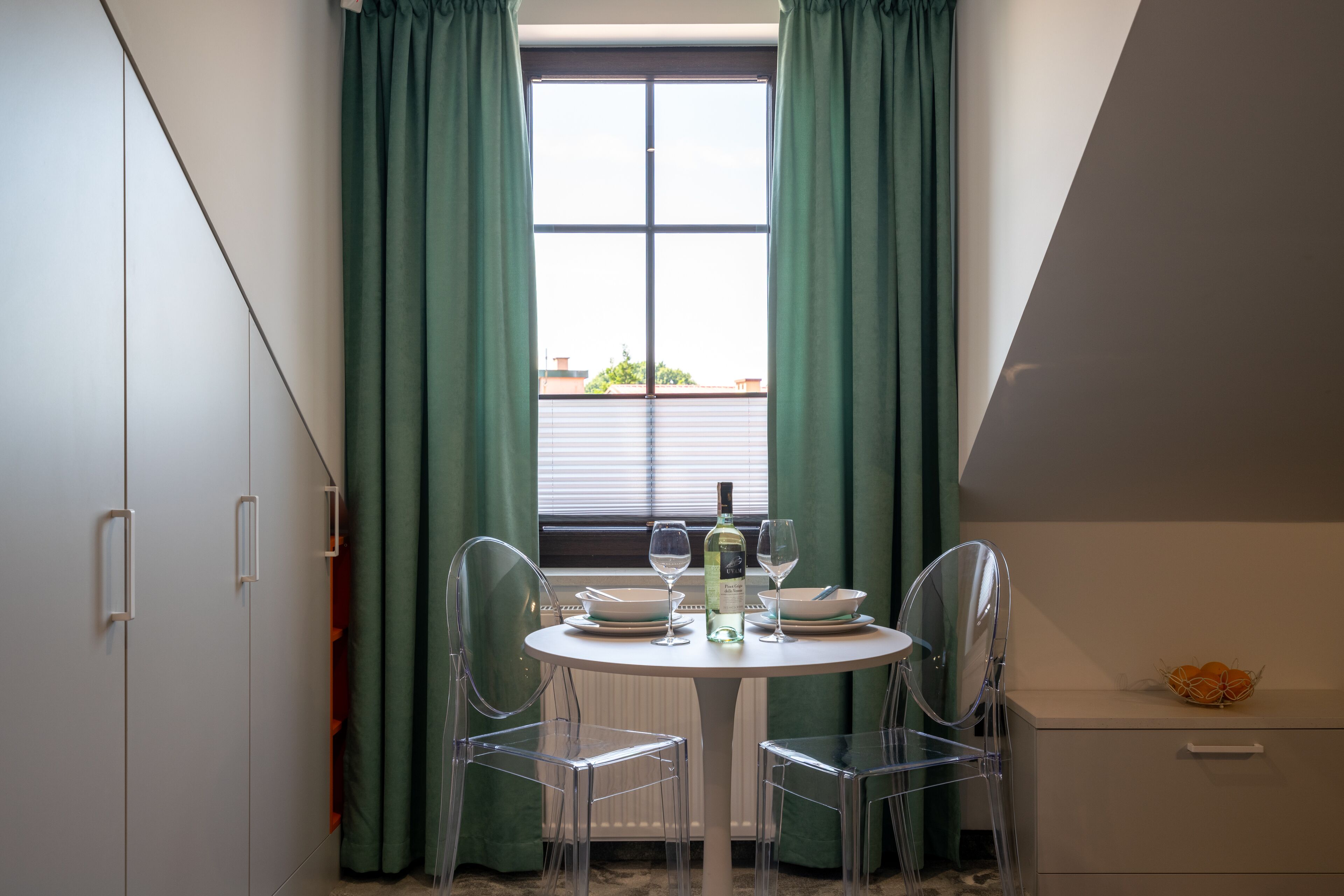 Een eetgedeelte met een ronde tafel, twee stoelen, een fles en twee glazen.