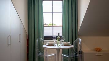 Een eetgedeelte met een ronde tafel, twee stoelen, een fles en twee glazen.