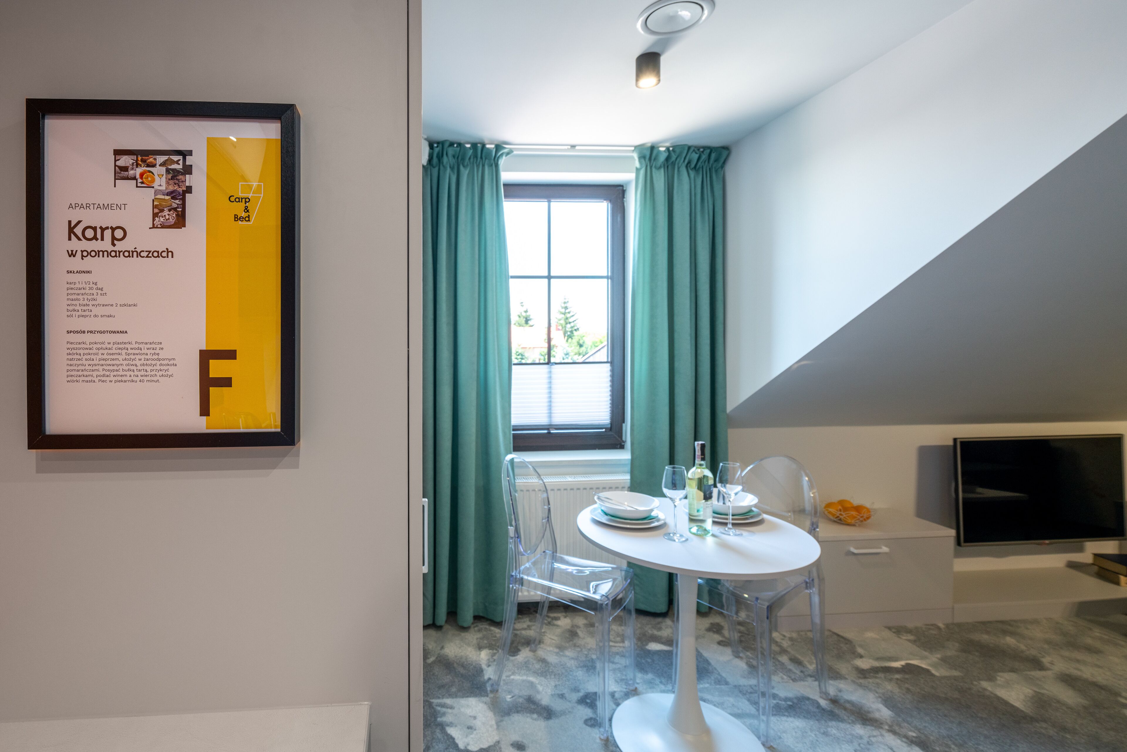 Een modern appartement met een eetgedeelte, met een ronde tafel, transparante stoelen en een televisie op een wit kastje.