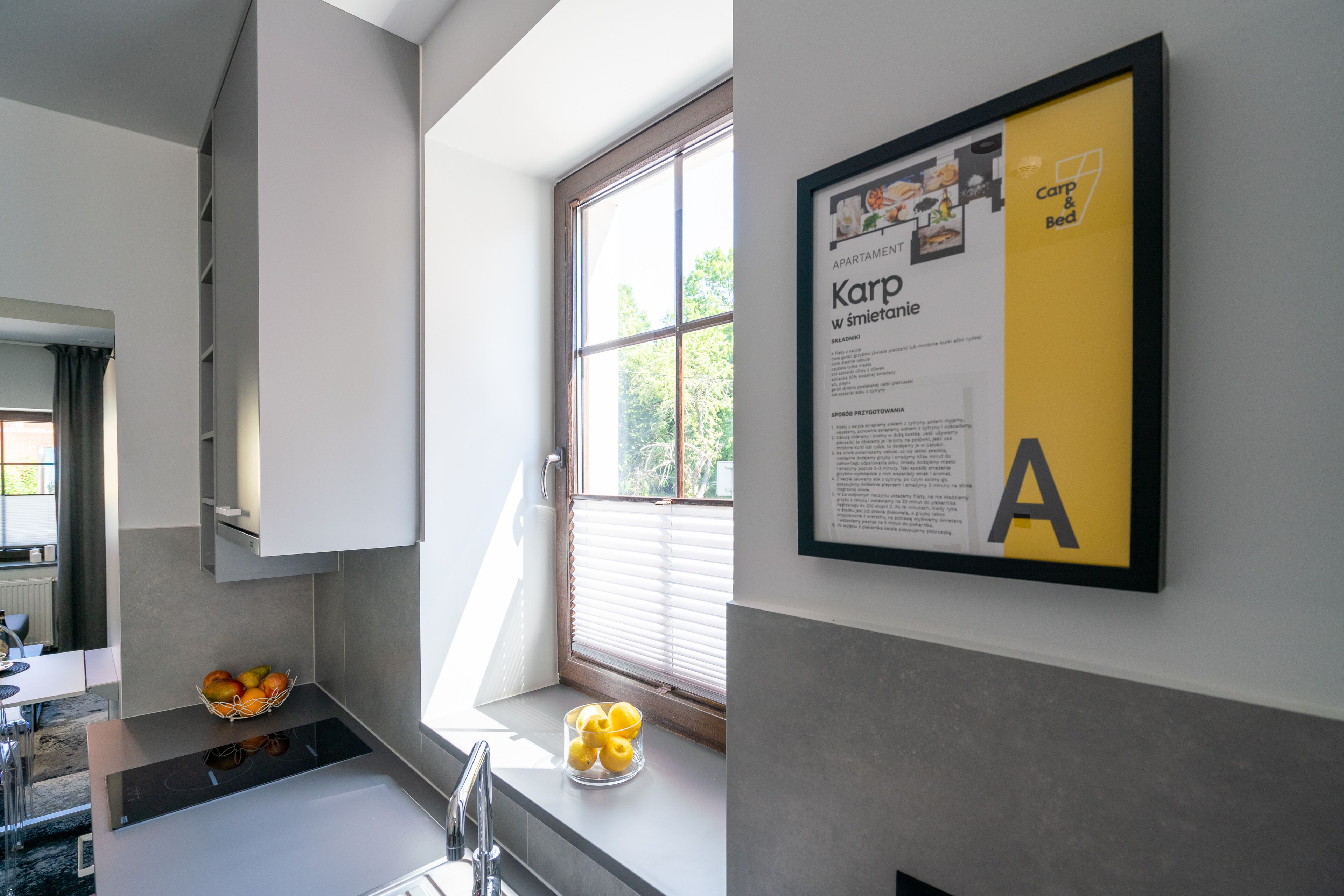 Una cocina moderna con horno empotrado, una ventana con persianas y un menú enmarcado en la pared.