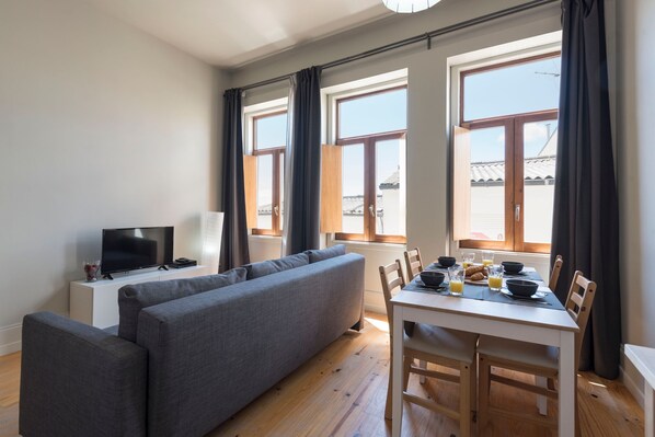A modern living room with a sofa, TV, dining table, and breakfast setup.