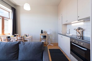A modern kitchen with white cabinets, a built-in oven, and a dining area with a wooden table and chairs.